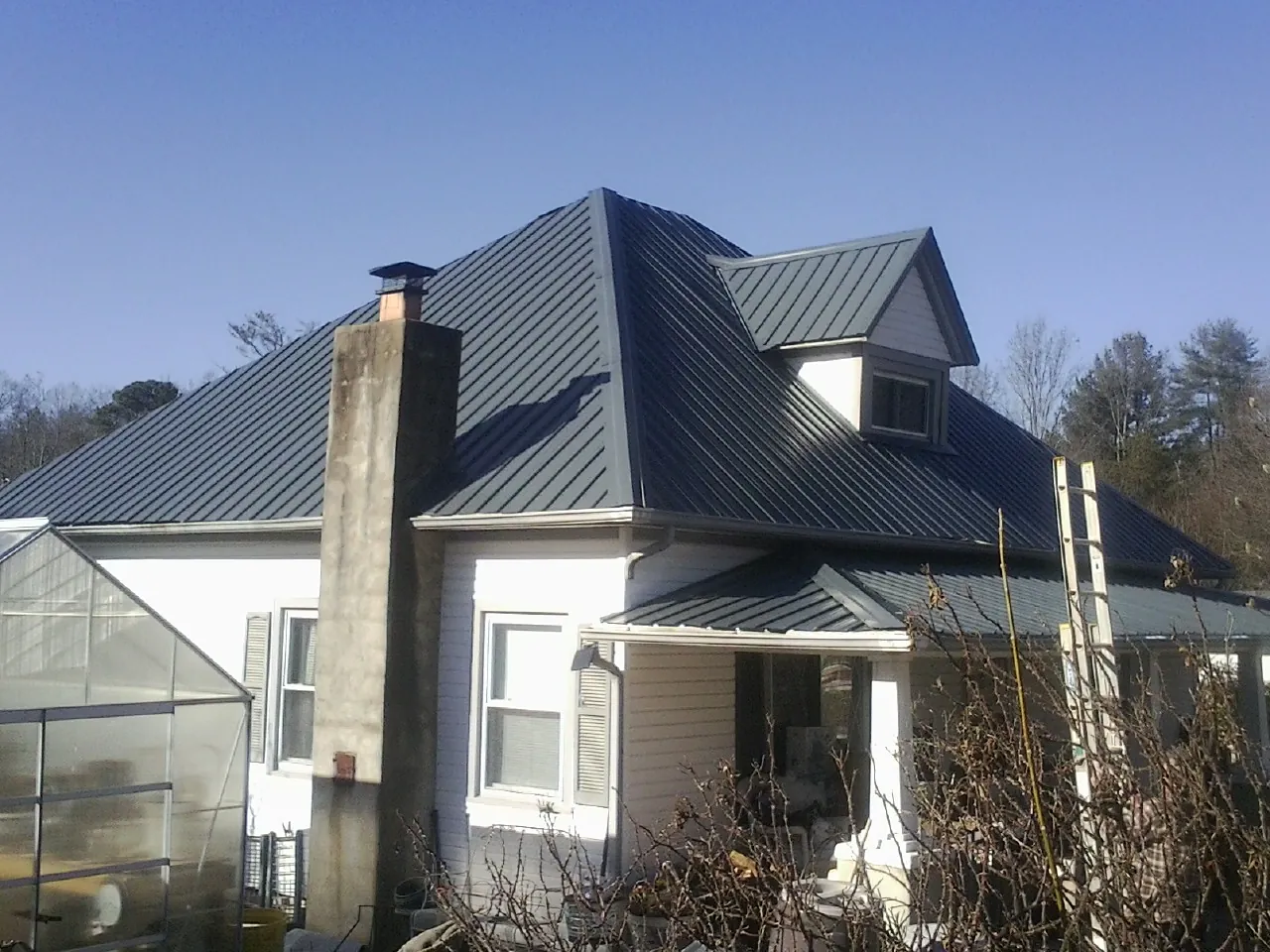 Dark blue standing seam metal roof on a white farmhouse with dormer — Slate & Tile Roof Repair by Roofing Brothers in Weogufka