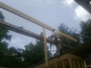 Carpenter setting a ridge beam over a new addition frame — Ice Dam Removal by Roofing Brothers in Weogufka