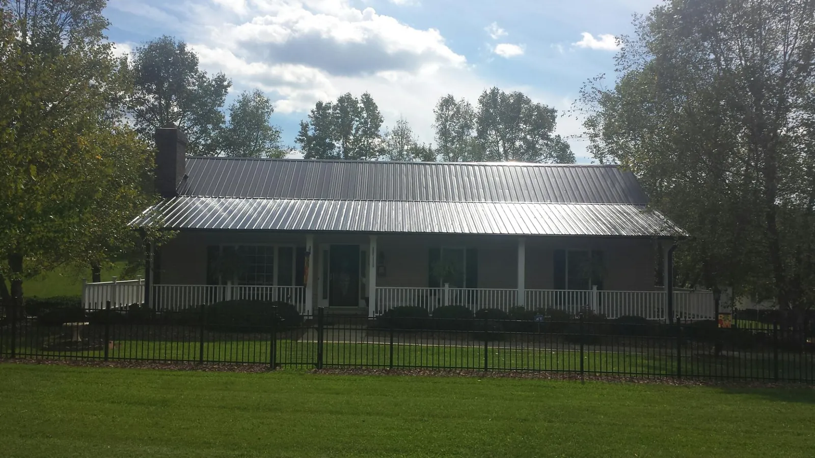 Gray metal roof on a brick ranch with a full width front porch — Gutter Guard Installation work by our crew in Weogufka