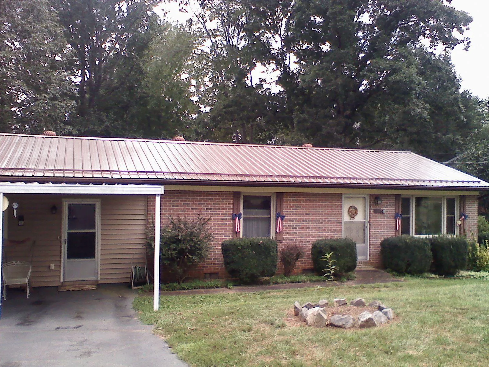 Bronze metal roof and carport on a brick ranch home — Roof Repair work by our crew in Weogufka