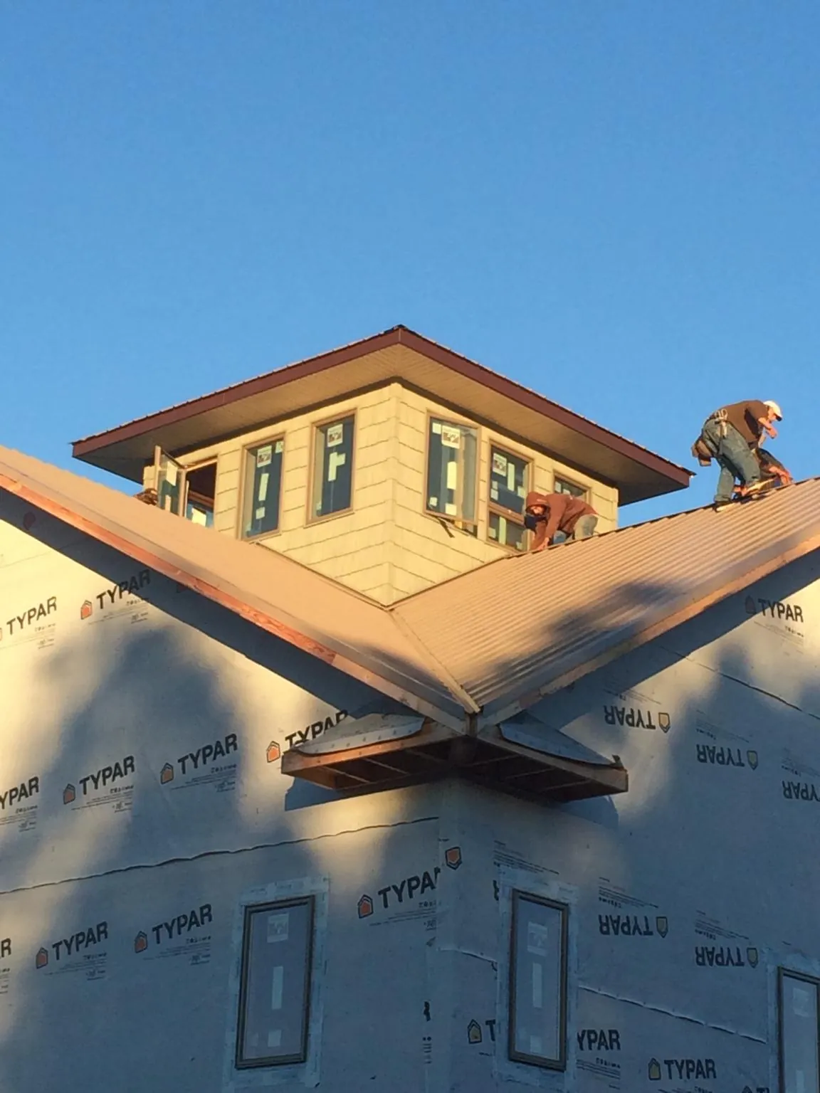 Roofers working around a rooftop cupola on a new metal roof at sunset — Roof Waterproofing in Weogufka by Roofing Brothers